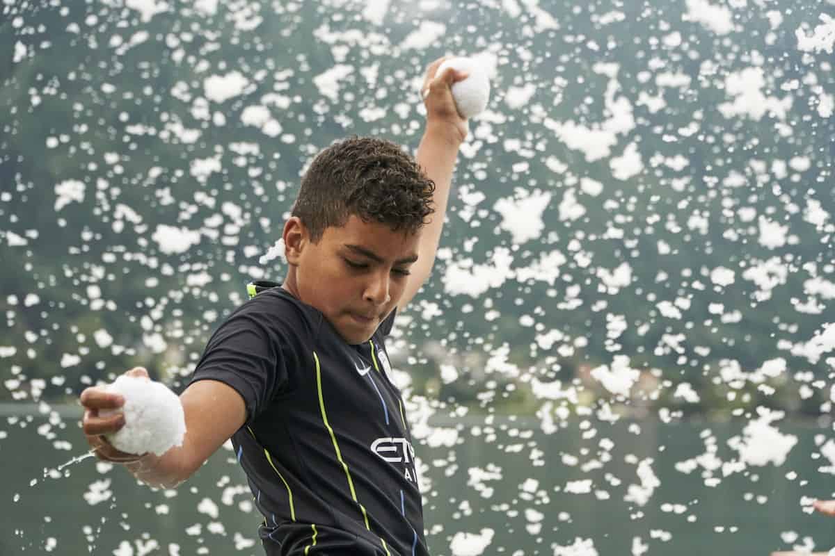 Child with snowballs during a pool snow event